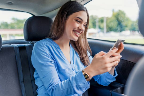 nice beautiful young woman smile and use mobile phone touching the screen inside the car while travel. modern concept of search hings and contact friends when you are away. daily use of smartphone